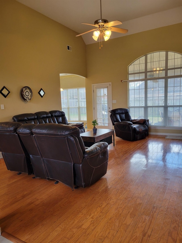 living room with high vaulted ceiling, ceiling fan, and light wood-type flooring