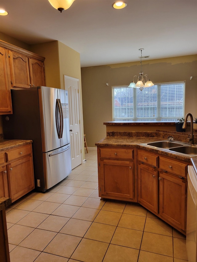 kitchen featuring sink, decorative light fixtures, light tile patterned floors, stainless steel fridge, and dishwasher