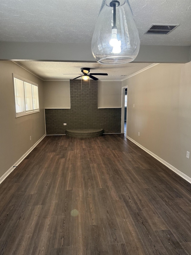 empty room featuring crown molding, ceiling fan, dark hardwood / wood-style floors, a textured ceiling, and brick wall