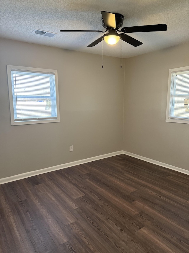 empty room with ceiling fan, dark hardwood / wood-style floors, and a textured ceiling