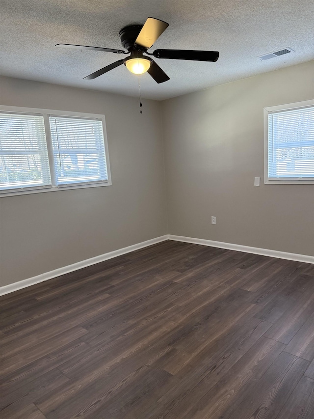 empty room featuring dark hardwood / wood-style flooring, ceiling fan, and a textured ceiling