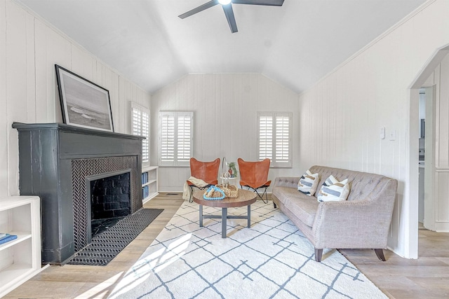 living room with plenty of natural light, a fireplace, vaulted ceiling, and light hardwood / wood-style flooring