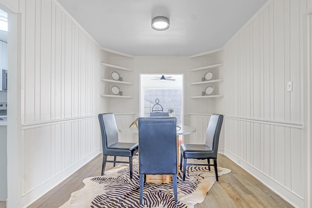 dining area featuring ornamental molding, built in features, and light hardwood / wood-style floors