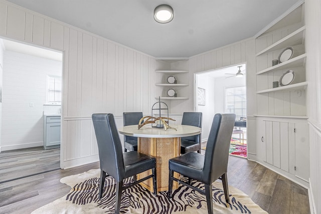 dining space with crown molding, light hardwood / wood-style flooring, and built in shelves