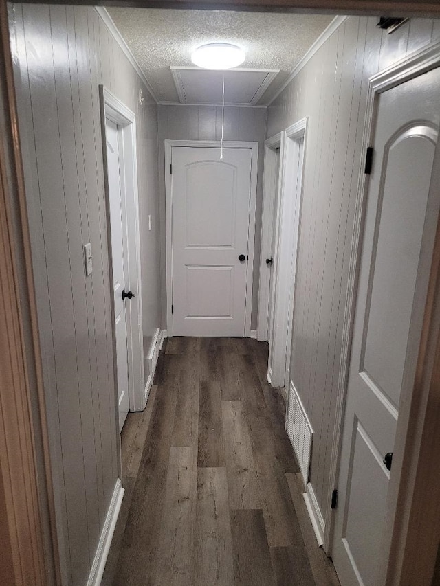 hallway with ornamental molding, dark hardwood / wood-style floors, and a textured ceiling