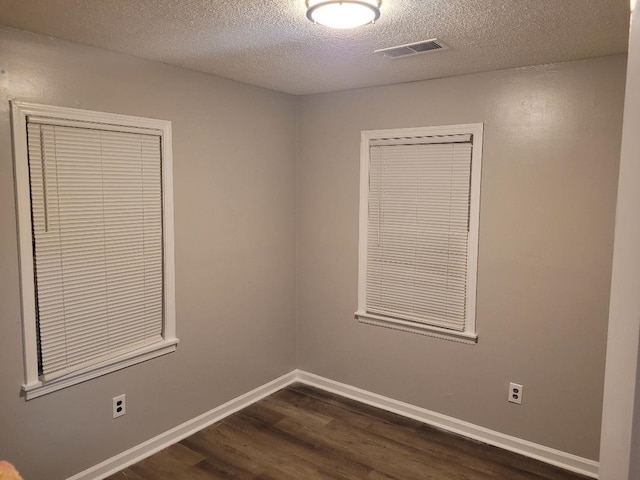 spare room featuring dark wood-type flooring and a textured ceiling