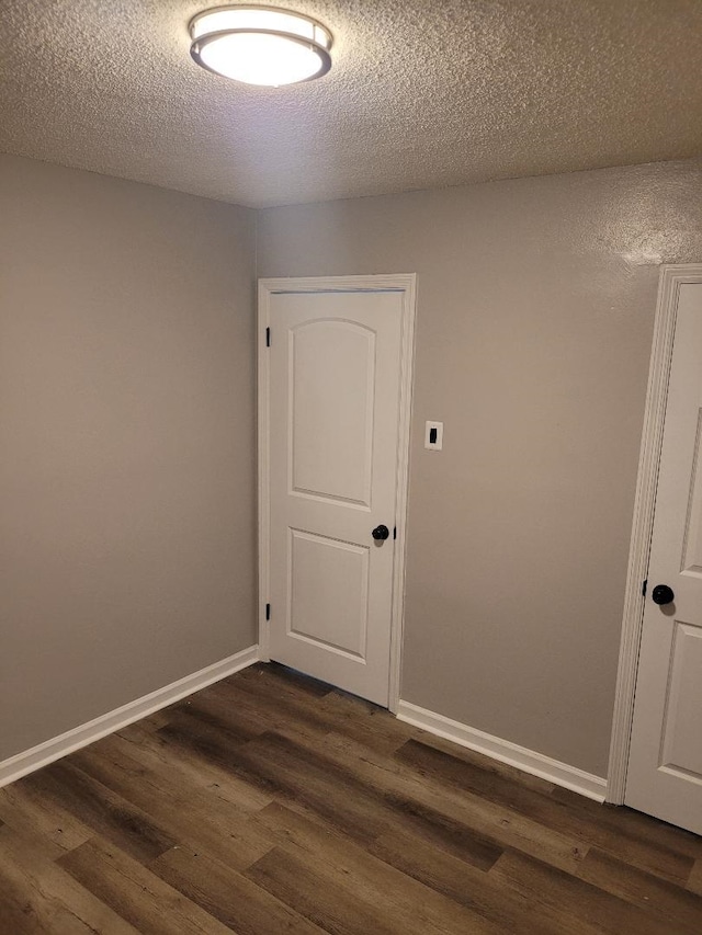 unfurnished room featuring dark wood-type flooring and a textured ceiling