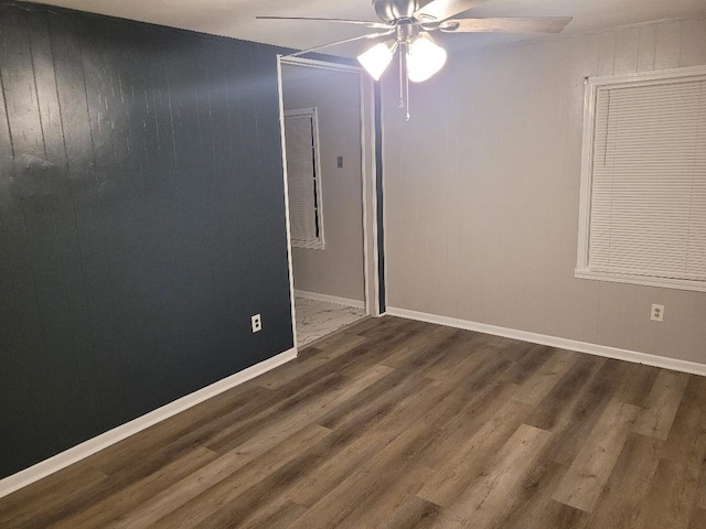 spare room featuring dark hardwood / wood-style floors, ceiling fan, and wood walls