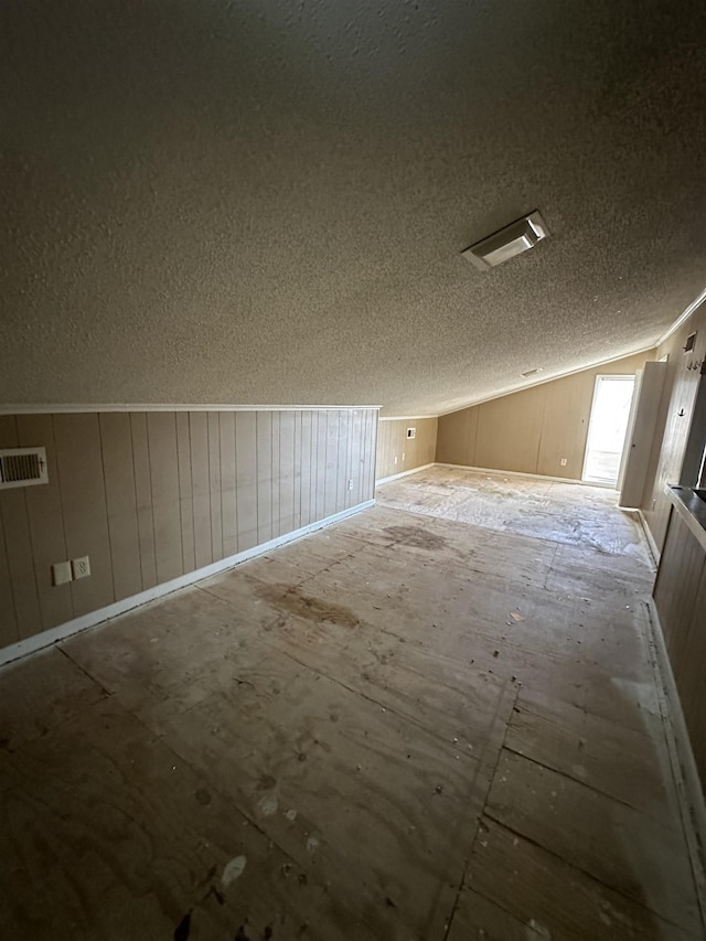 additional living space with lofted ceiling and a textured ceiling