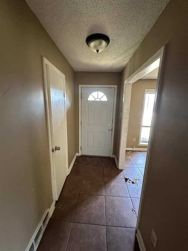 doorway featuring dark tile patterned flooring and a textured ceiling