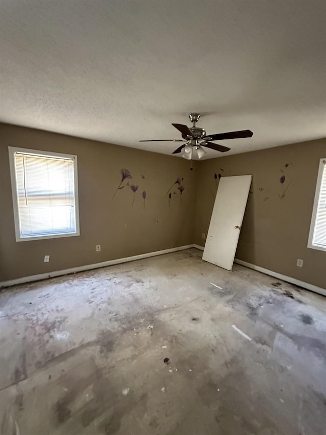 unfurnished room with ceiling fan and a textured ceiling