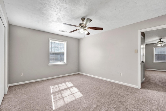 carpeted spare room with ceiling fan and a textured ceiling