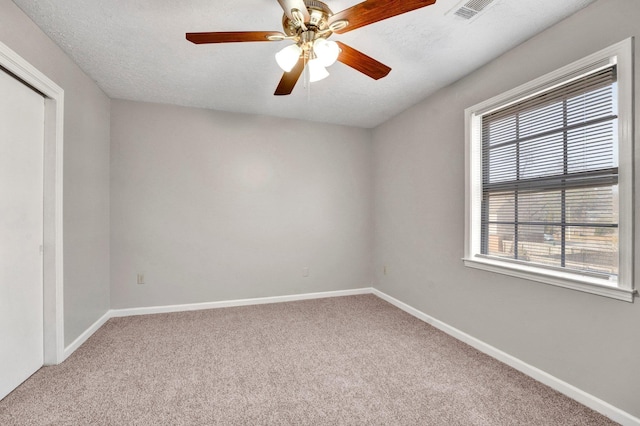 unfurnished room with light carpet, ceiling fan, and a textured ceiling