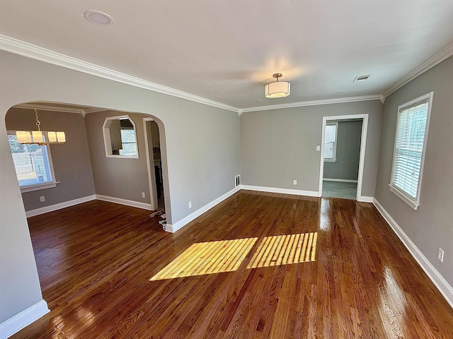 empty room with a wealth of natural light, dark wood-type flooring, and ornamental molding