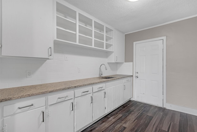 kitchen with dark hardwood / wood-style flooring, sink, backsplash, and white cabinets