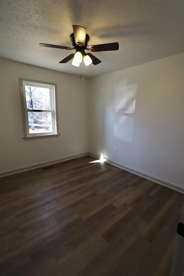 empty room with ceiling fan, dark wood-type flooring, and a textured ceiling