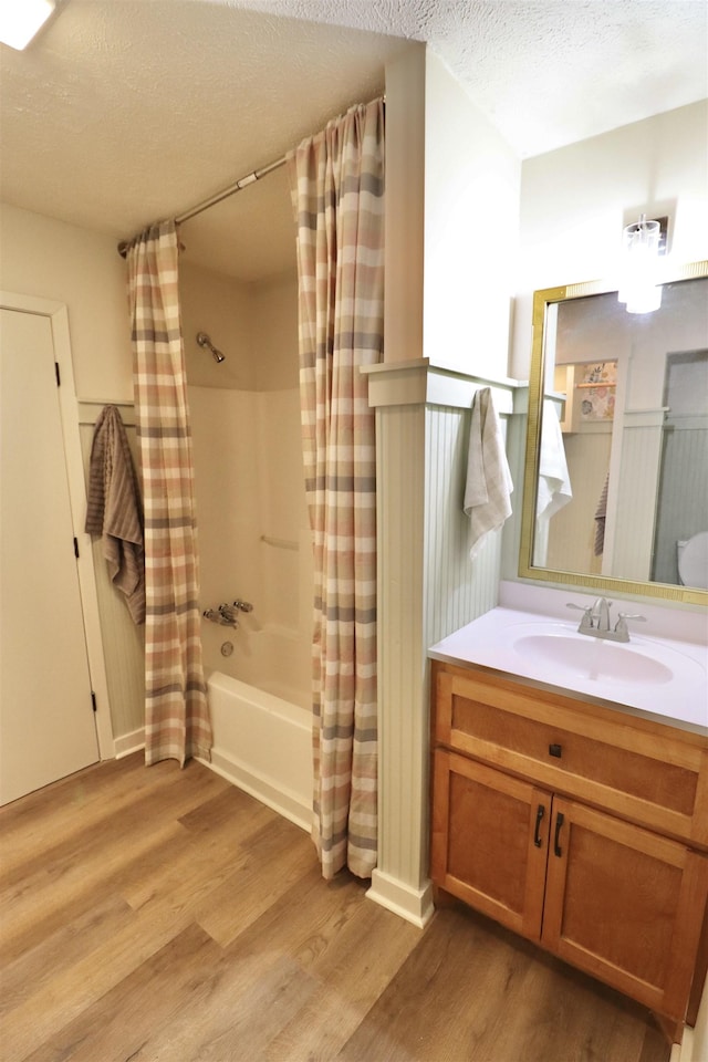 bathroom with wood-type flooring, shower / bath combination with curtain, a textured ceiling, and vanity