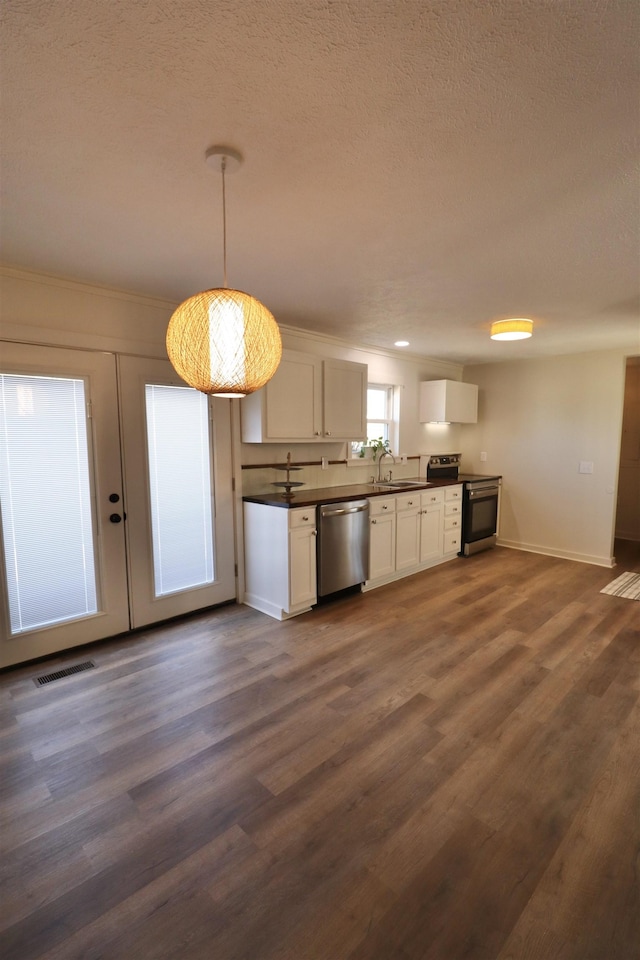 kitchen featuring pendant lighting, sink, appliances with stainless steel finishes, white cabinetry, and dark hardwood / wood-style flooring