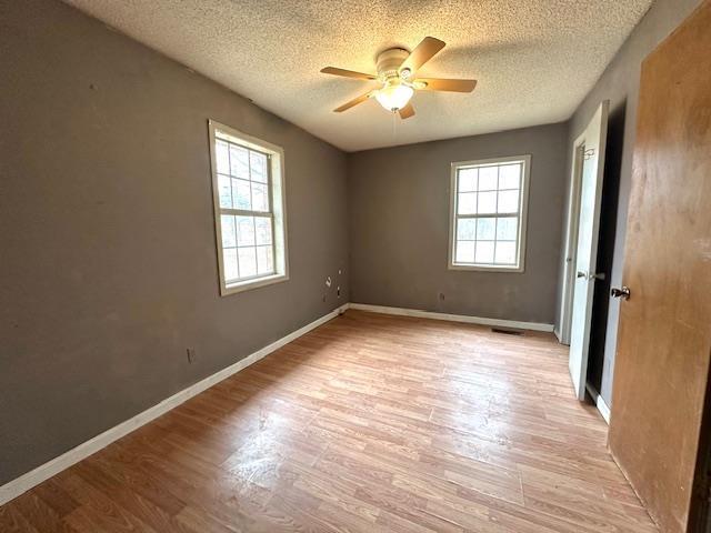 spare room with ceiling fan, a textured ceiling, and light wood-type flooring