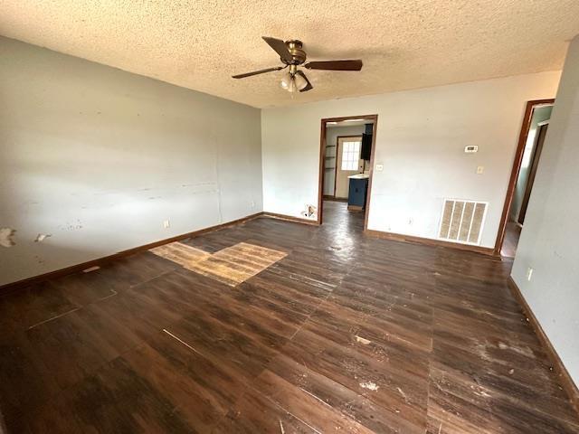 unfurnished room with ceiling fan, dark wood-type flooring, and a textured ceiling