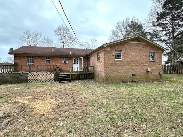 rear view of house featuring a wooden deck and a yard