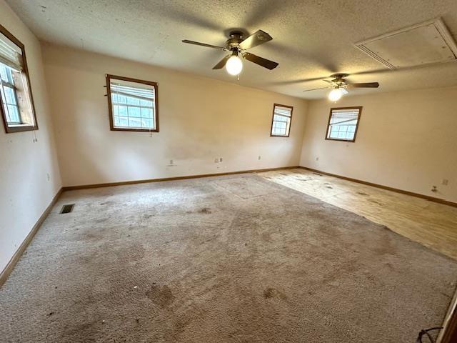 carpeted spare room featuring ceiling fan and a textured ceiling