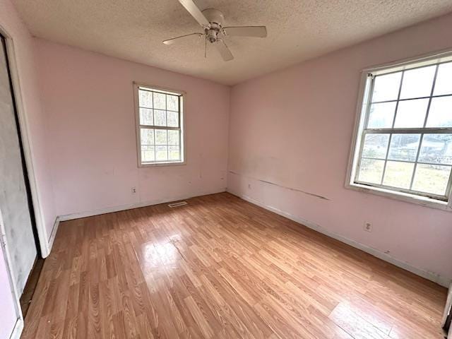 empty room featuring ceiling fan, a textured ceiling, and light wood-type flooring