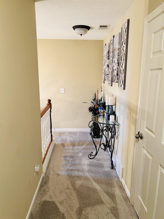 hall featuring carpet floors and a textured ceiling