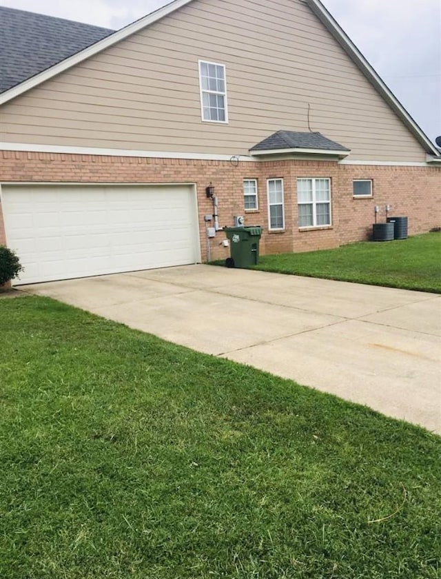 view of side of property with cooling unit, a garage, and a lawn