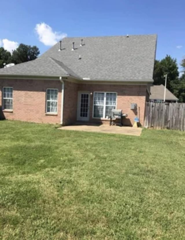 back of house with a lawn and a patio