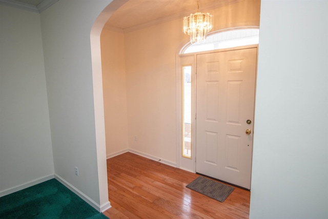 foyer featuring wood-type flooring, ornamental molding, a wealth of natural light, and a notable chandelier