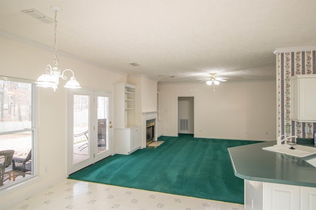 unfurnished living room with sink, ceiling fan with notable chandelier, and carpet flooring