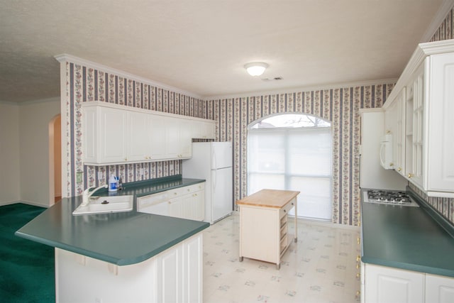 kitchen with white cabinetry, sink, crown molding, and white appliances