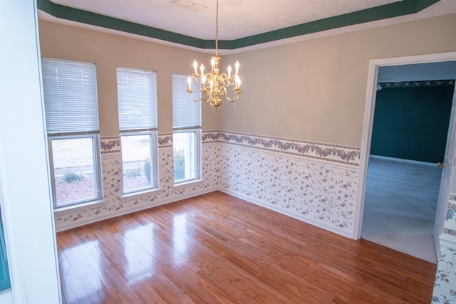 spare room featuring hardwood / wood-style flooring and an inviting chandelier