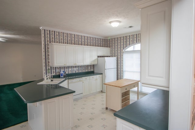 kitchen with sink, white appliances, a textured ceiling, white cabinets, and kitchen peninsula