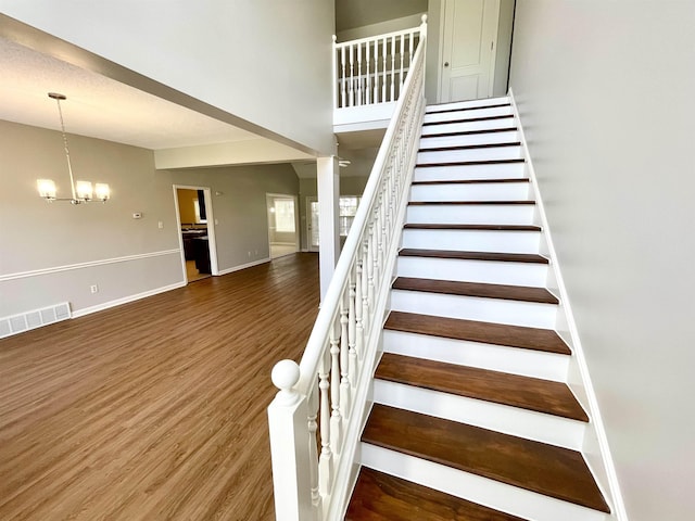 stairway featuring hardwood / wood-style floors and a notable chandelier