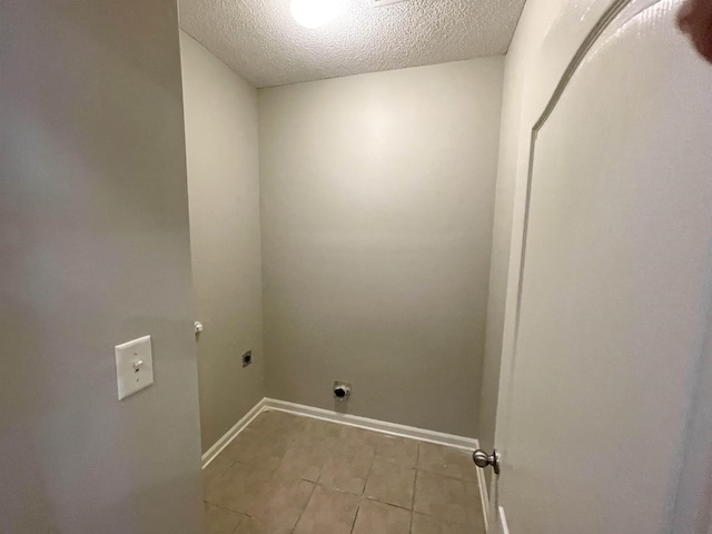 laundry room with electric dryer hookup, light tile patterned floors, and a textured ceiling