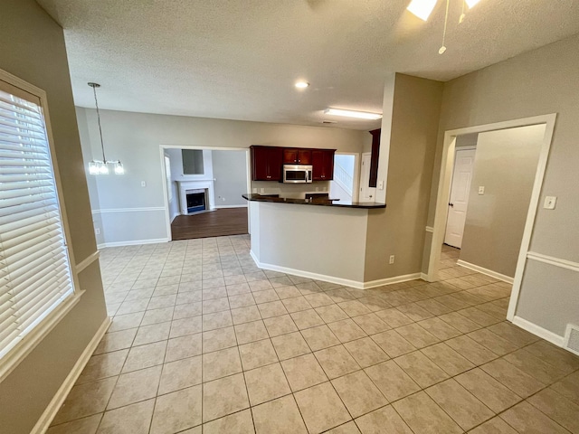 kitchen with light tile patterned flooring, decorative light fixtures, kitchen peninsula, and a textured ceiling