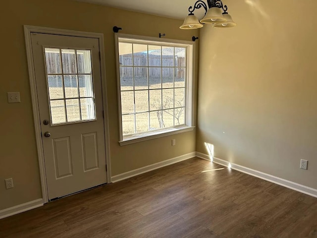 doorway to outside with dark hardwood / wood-style floors and a notable chandelier