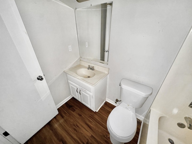 bathroom with vanity, baseboards, toilet, a shower, and wood finished floors