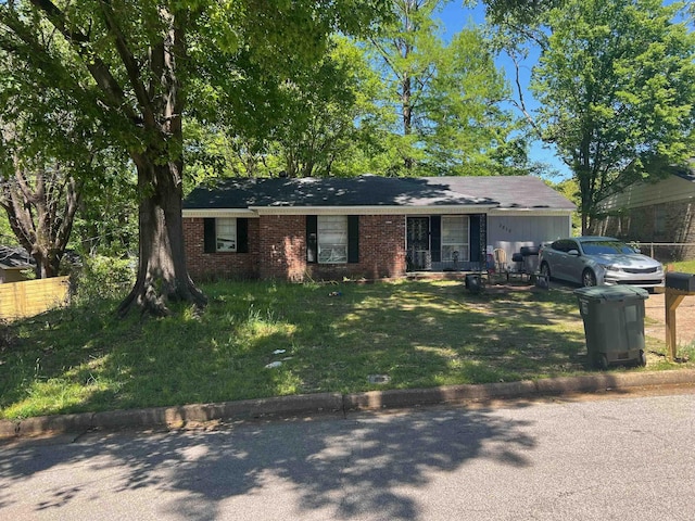 single story home with brick siding, an attached garage, a front lawn, and fence