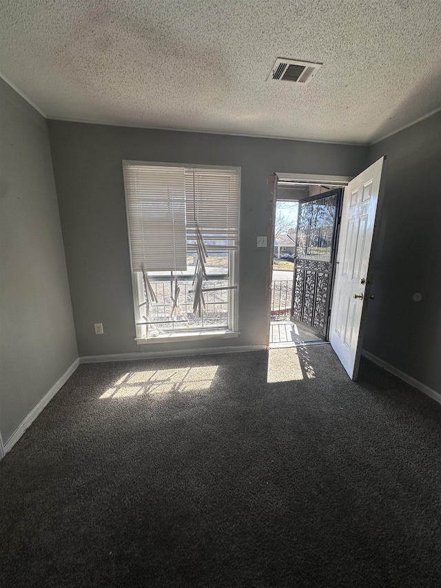 carpeted spare room featuring baseboards, visible vents, and a textured ceiling