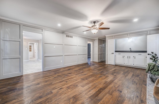 unfurnished living room with sink, ornamental molding, dark hardwood / wood-style floors, and ceiling fan