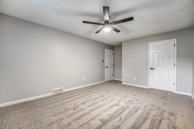 empty room with a textured ceiling, light colored carpet, and ceiling fan