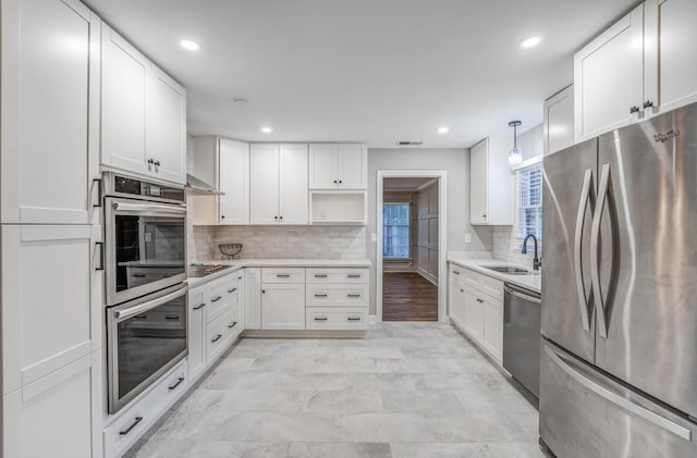 kitchen featuring white cabinetry, appliances with stainless steel finishes, decorative light fixtures, and sink