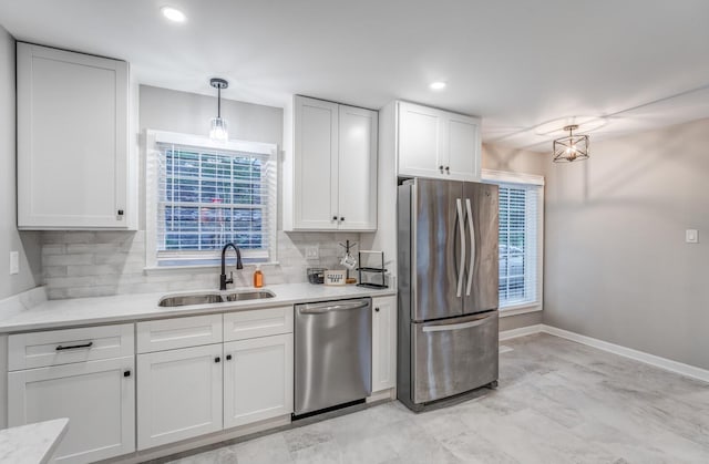 kitchen with pendant lighting, sink, appliances with stainless steel finishes, white cabinetry, and backsplash