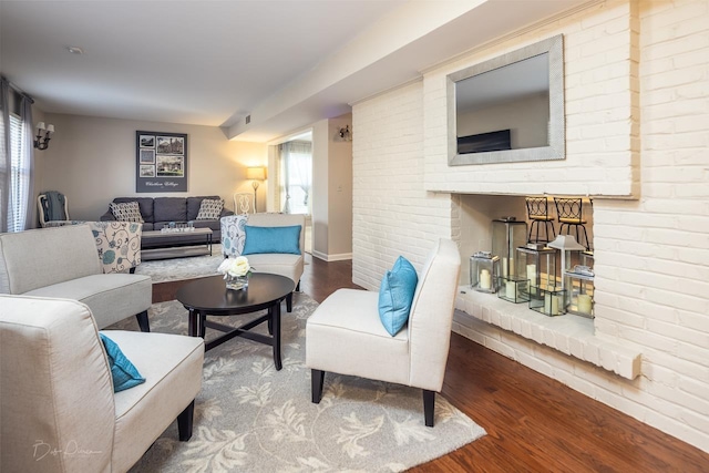 living room with hardwood / wood-style flooring, brick wall, and a wealth of natural light