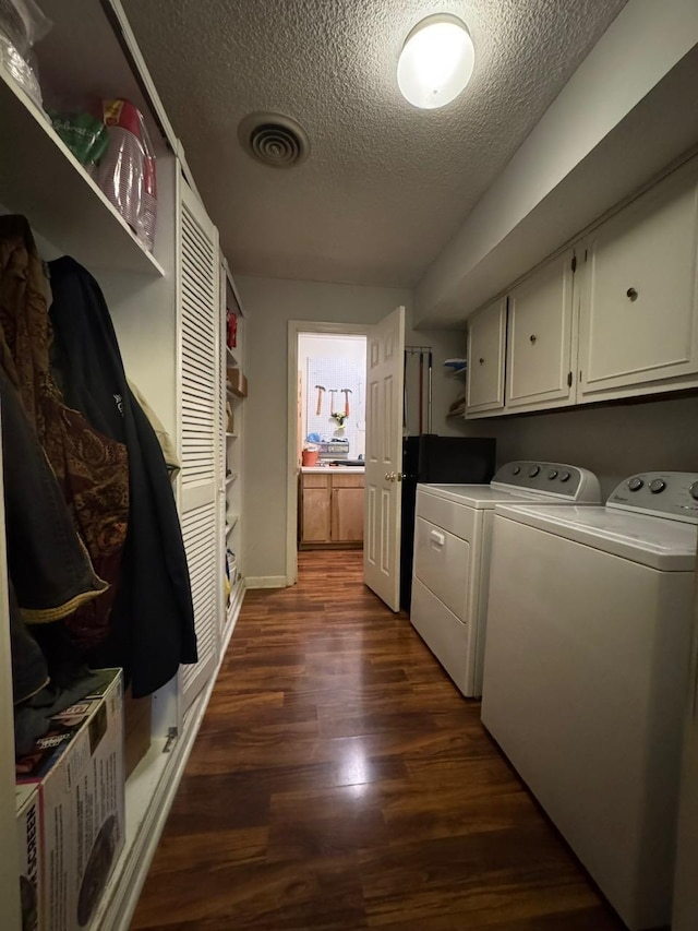 clothes washing area with dark wood-type flooring, cabinets, washer and dryer, and a textured ceiling