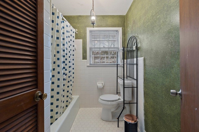 bathroom featuring shower / bath combination with curtain, tile walls, tile patterned floors, and toilet