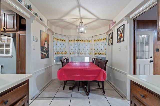 dining space with a textured ceiling and light tile patterned floors